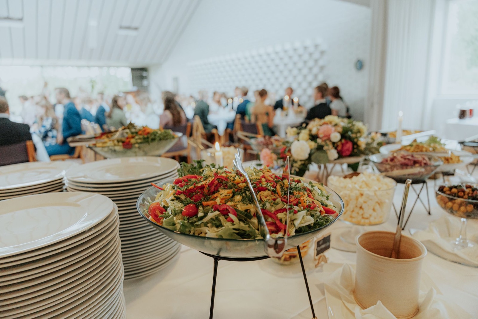 Värikkäitä salaatteja juhlabuffetissa, vieraat taustalla