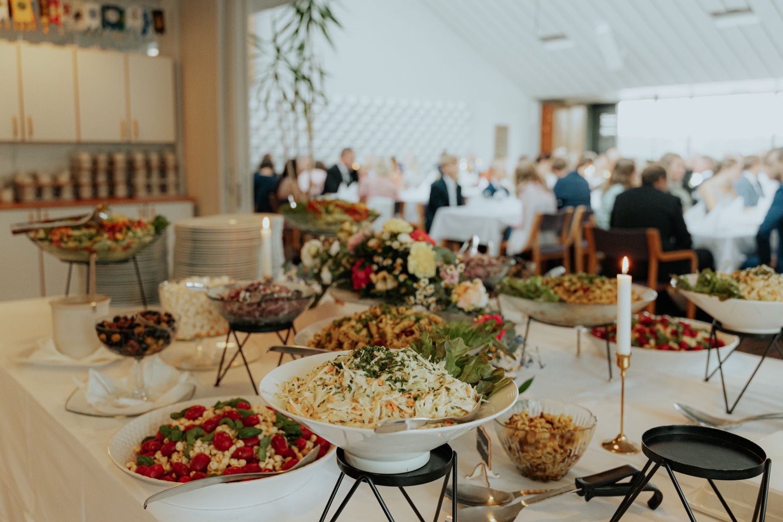 Juhlabuffet kynttilöineen ja juhlavieraat taustalla