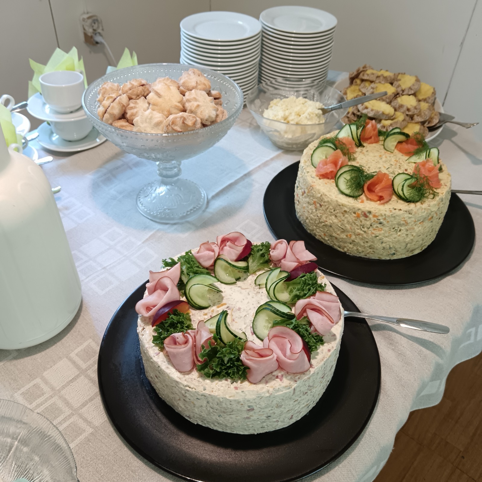 Kaksi käsin koristeltua voileipäkakkua kahvipöydässä